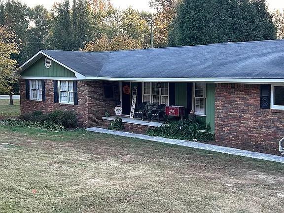 ranch-style home featuring covered porch and brick siding
