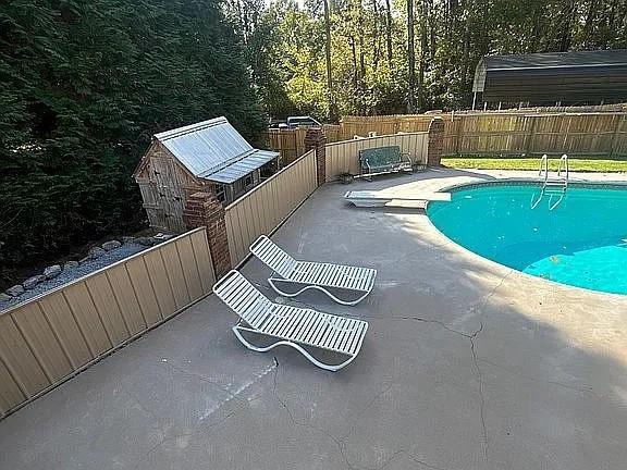 view of pool featuring a diving board, fence, a patio area, and a fenced in pool