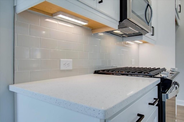 101 Priestwood Ln, Acworth, GA 30102 - kitchen with stainless steel gas range, decorative backsplash, white cabinetry, and light stone countertops
