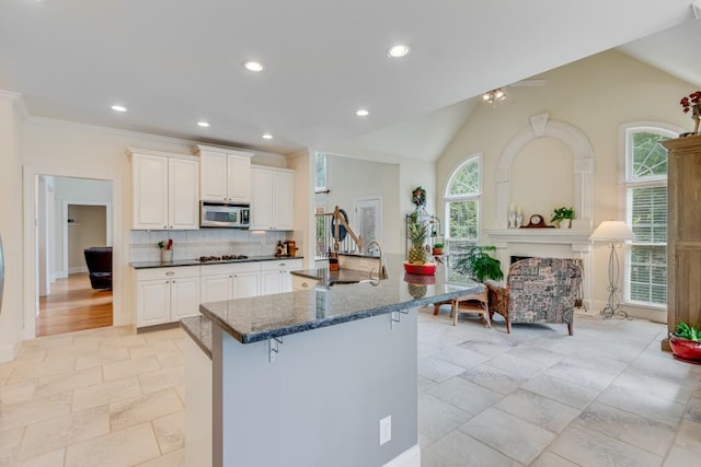 5359 Point S Dr, Gainesville, GA 30504 - kitchen featuring stainless steel microwave, a kitchen breakfast bar, backsplash, white cabinets, and dark stone countertops