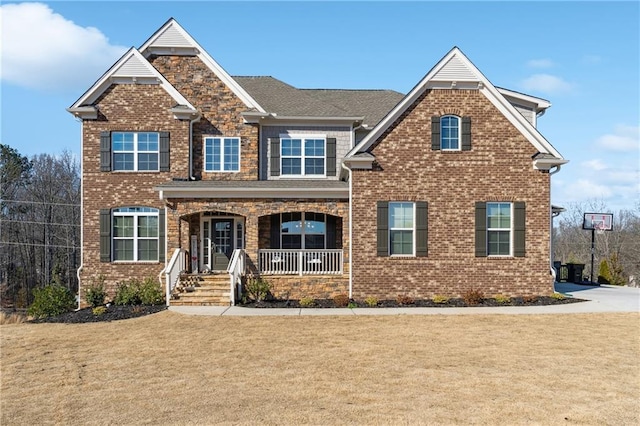 craftsman-style house featuring covered porch, a front lawn, and brick siding