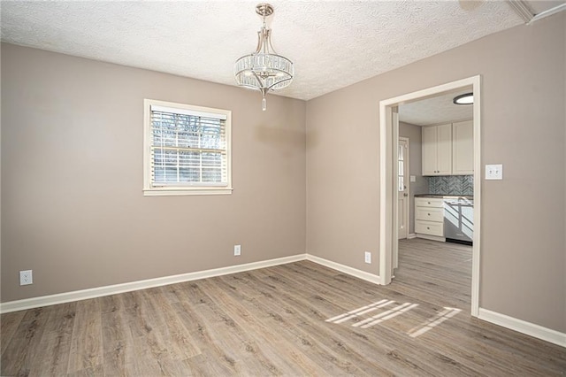 1312 La Mesa Dr, Lawrenceville, GA 30043 - unfurnished dining area featuring light wood-type flooring, a textured ceiling, a chandelier, and baseboards