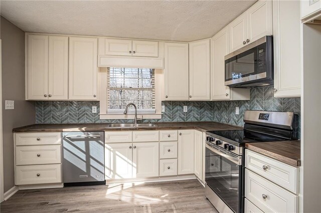 1312 La Mesa Dr, Lawrenceville, GA 30043 - kitchen with stainless steel appliances, a sink, light wood-style flooring, a textured ceiling, and white cabinets