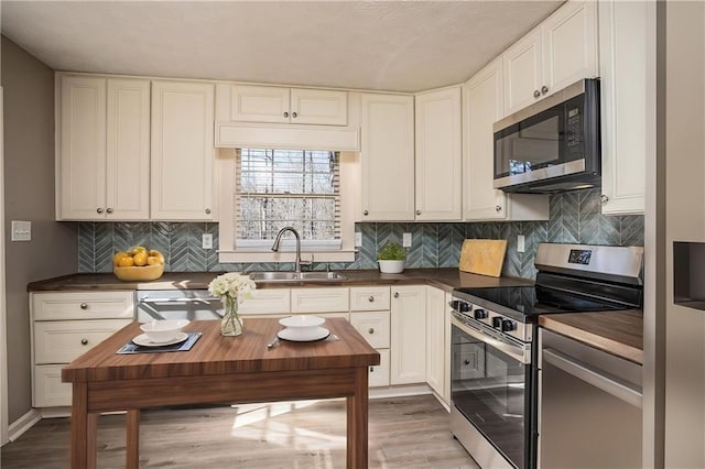1312 La Mesa Dr, Lawrenceville, GA 30043 - kitchen with appliances with stainless steel finishes, a sink, light wood finished floors, and white cabinets