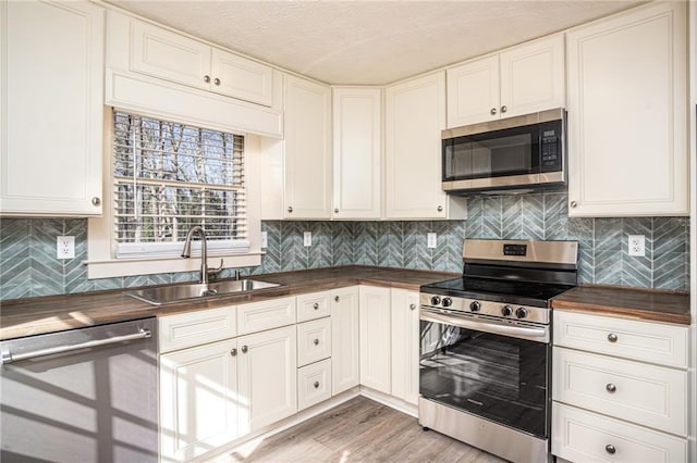 1312 La Mesa Dr, Lawrenceville, GA 30043 - kitchen with appliances with stainless steel finishes, wooden counters, a sink, light wood-type flooring, and decorative backsplash