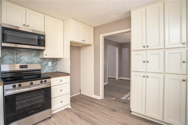 1312 La Mesa Dr, Lawrenceville, GA 30043 - kitchen with appliances with stainless steel finishes, decorative backsplash, baseboards, light wood-style flooring, and a textured ceiling
