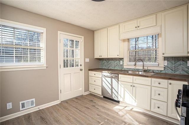 1312 La Mesa Dr, Lawrenceville, GA 30043 - kitchen featuring dishwasher, a sink, healthy amount of natural light, backsplash, and a textured ceiling