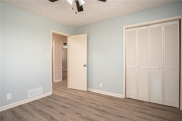 1312 La Mesa Dr, Lawrenceville, GA 30043 - unfurnished bedroom featuring wood finished floors, baseboards, a closet, a textured ceiling, and ceiling fan