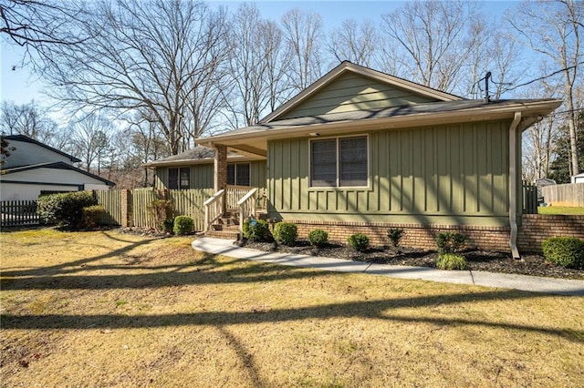 view of front of property with board and batten siding, a front yard, and fence