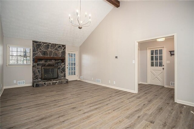 1312 La Mesa Dr, Lawrenceville, GA 30043 - unfurnished living room featuring a chandelier, beam ceiling, wood finished floors, a stone fireplace, and high vaulted ceiling