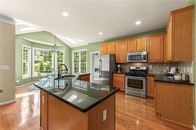 1995 Settindown Dr, Roswell, GA 30075 - kitchen featuring appliances with stainless steel finishes, light wood finished floors, backsplash, a large island with sink, and vaulted ceiling