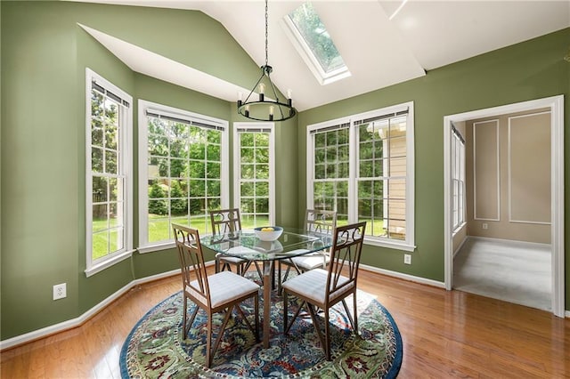 1995 Settindown Dr, Roswell, GA 30075 - dining space with lofted ceiling, a skylight, wood finished floors, and a chandelier
