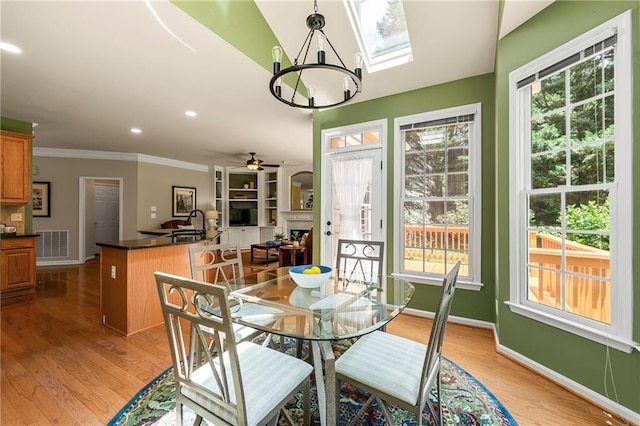 1995 Settindown Dr, Roswell, GA 30075 - dining space featuring a chandelier, a ceiling fan, light wood finished floors, ornamental molding, and a skylight