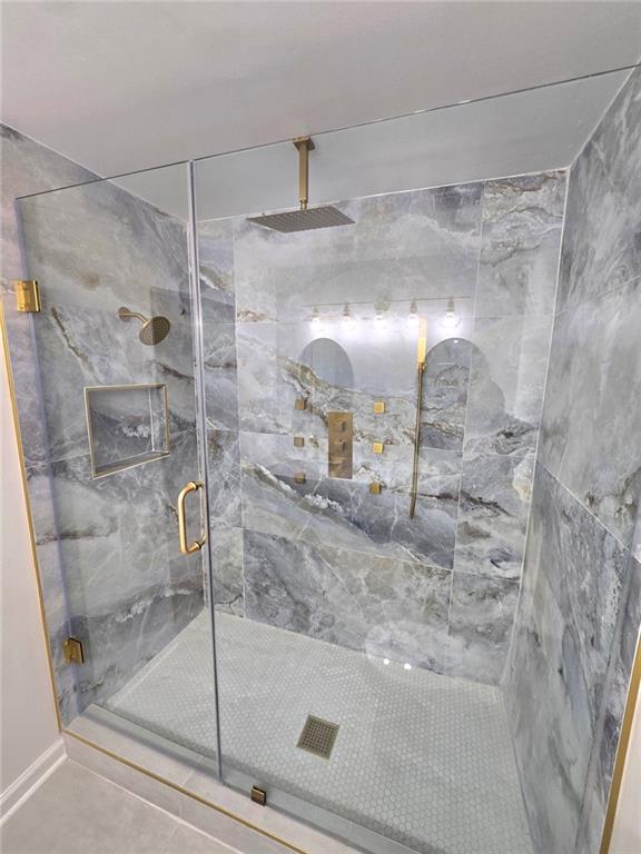 bathroom with a shower stall and tile patterned flooring