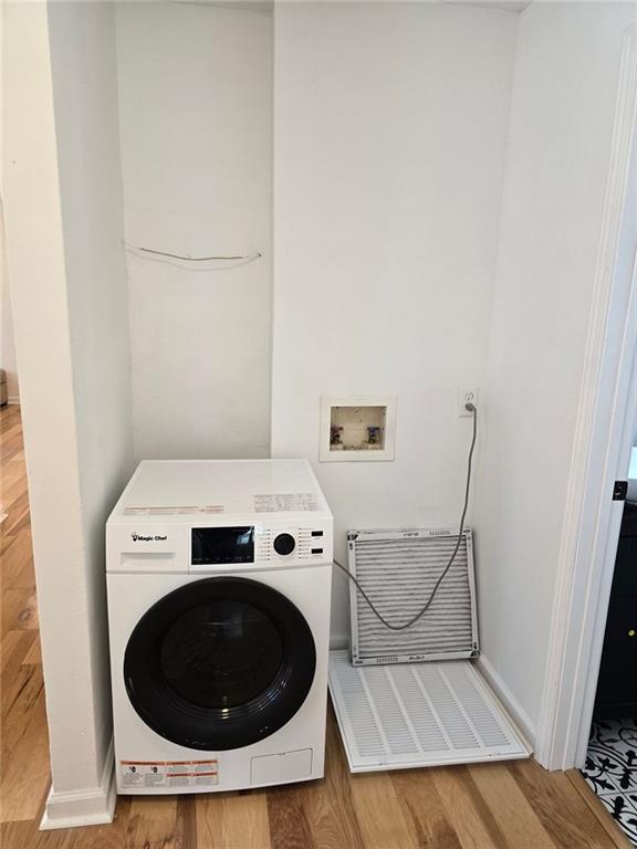 laundry area with laundry area, wood finished floors, washer / dryer, and baseboards