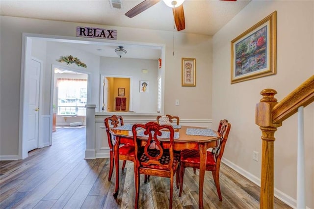 dining space with stairs, wood finished floors, a ceiling fan, and baseboards