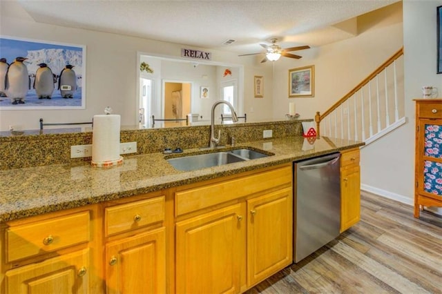 kitchen featuring light stone counters, a sink, light wood-type flooring, brown cabinets, and dishwasher