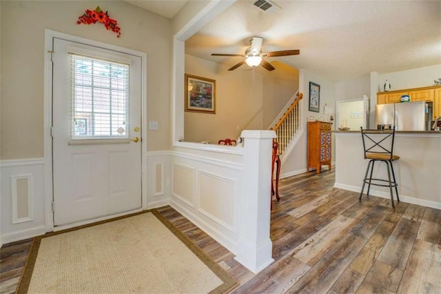 entryway with a wainscoted wall, stairway, a decorative wall, and dark wood-style flooring