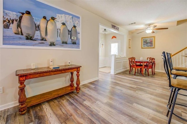 interior space with ceiling fan, wood finished floors, visible vents, baseboards, and stairs