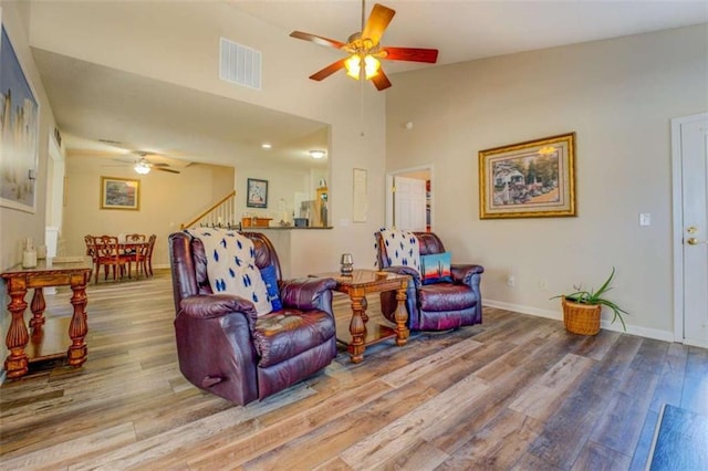 living room with a ceiling fan, visible vents, baseboards, and wood finished floors