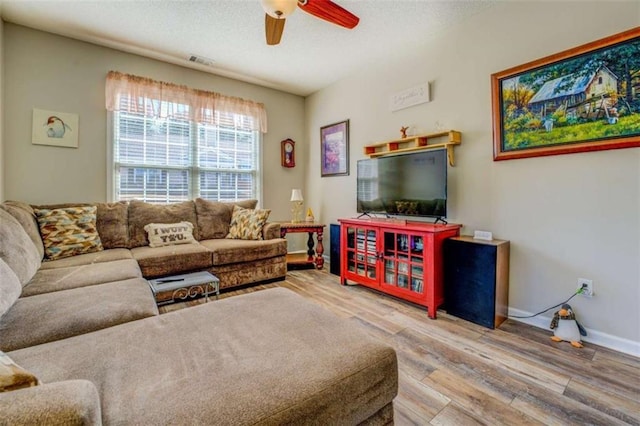 living room featuring baseboards, visible vents, ceiling fan, wood finished floors, and a textured ceiling