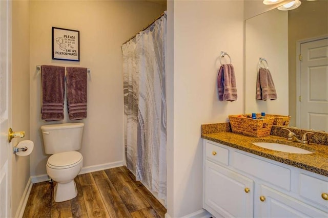 full bath with toilet, baseboards, wood finished floors, and vanity