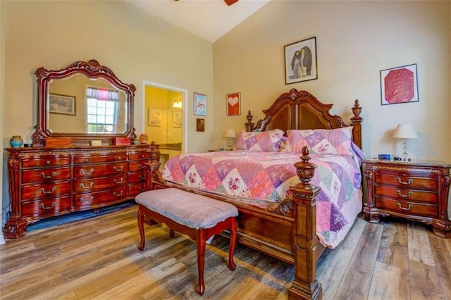 bedroom with ceiling fan, lofted ceiling, connected bathroom, and wood finished floors