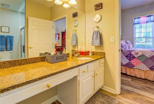 ensuite bathroom featuring a stall shower, connected bathroom, toilet, wood finished floors, and vanity