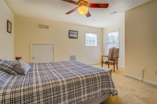 bedroom featuring light colored carpet, visible vents, a textured ceiling, and baseboards