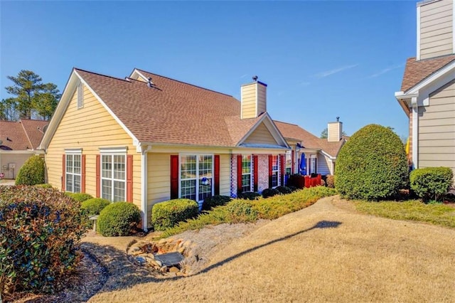 rear view of house featuring a shingled roof and a chimney