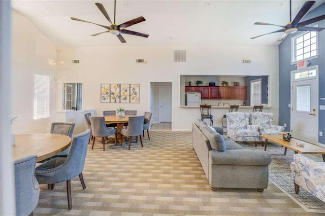 living area with high vaulted ceiling, visible vents, and a ceiling fan