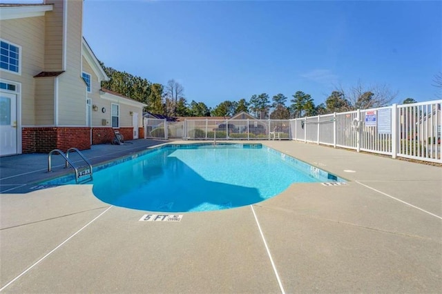 community pool with a patio area and fence