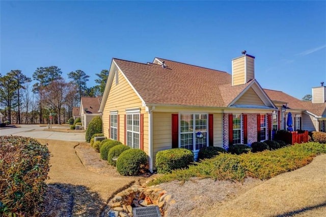 view of side of home featuring a shingled roof and a chimney