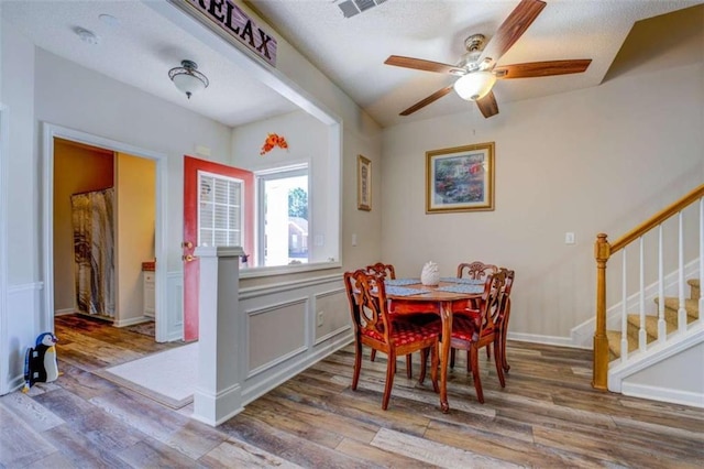 dining room with wood finished floors, visible vents, and stairs