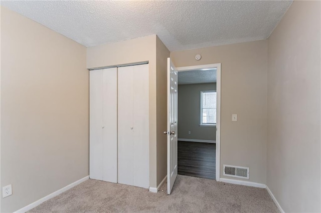 unfurnished bedroom with a closet, light carpet, and a textured ceiling