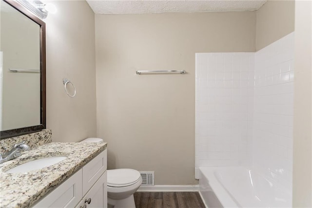 full bathroom featuring toilet, bathing tub / shower combination, wood-type flooring, a textured ceiling, and vanity