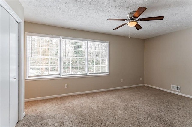 carpeted spare room featuring ceiling fan and a textured ceiling