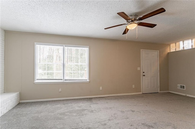 spare room featuring ceiling fan, light colored carpet, and a textured ceiling