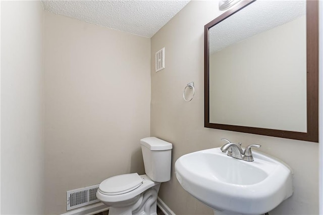 bathroom featuring sink, toilet, and a textured ceiling