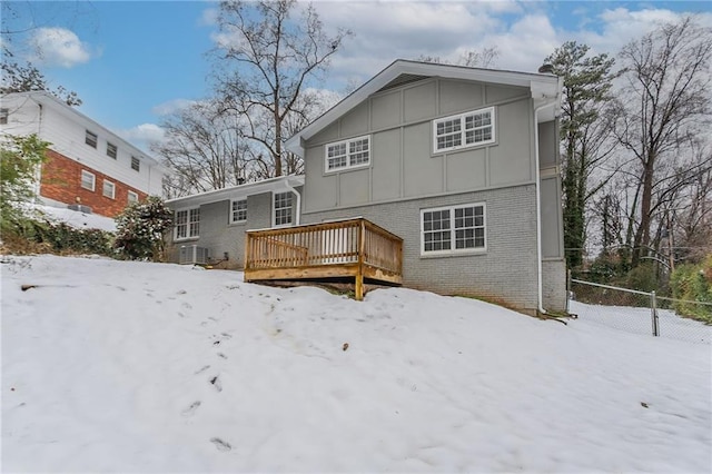 snow covered house featuring central AC and a deck