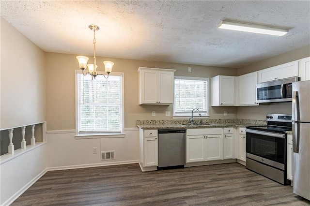 kitchen featuring sink, decorative light fixtures, stainless steel appliances, light stone countertops, and white cabinets