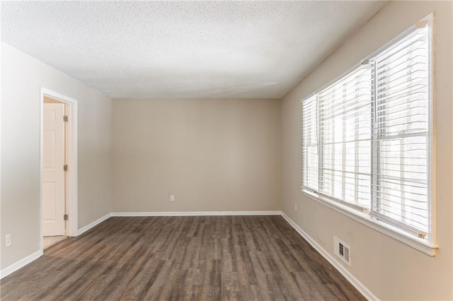 spare room featuring dark hardwood / wood-style floors and a textured ceiling