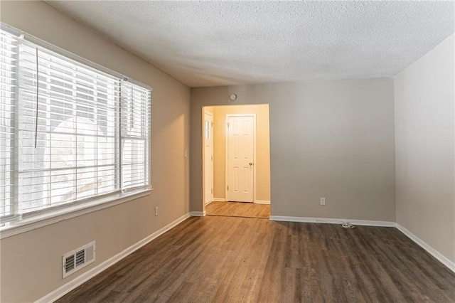 unfurnished room with dark hardwood / wood-style flooring and a textured ceiling