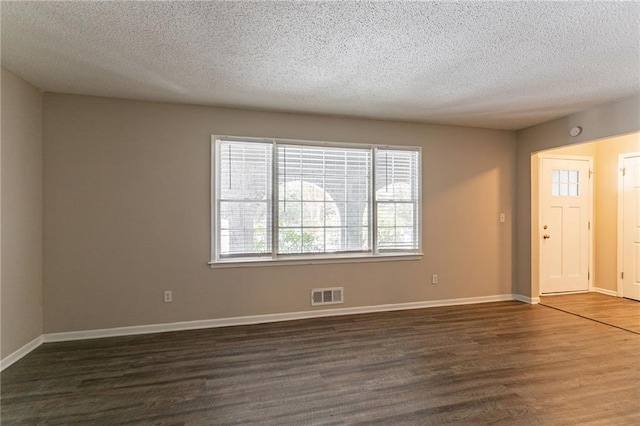 empty room featuring a textured ceiling and dark hardwood / wood-style flooring