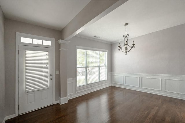 entrance foyer with ornamental molding, a chandelier, beamed ceiling, and dark hardwood / wood-style flooring