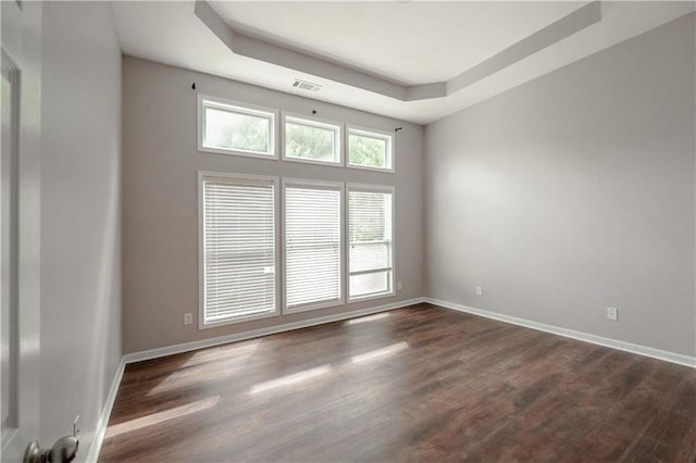 unfurnished room featuring a tray ceiling and dark wood-type flooring