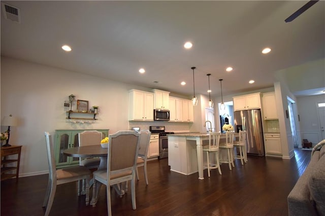 485 Broadmoor Dr, Braselton, GA 30517 - kitchen with stainless steel appliances, decorative backsplash, a kitchen breakfast bar, a kitchen island with sink, and white cabinets