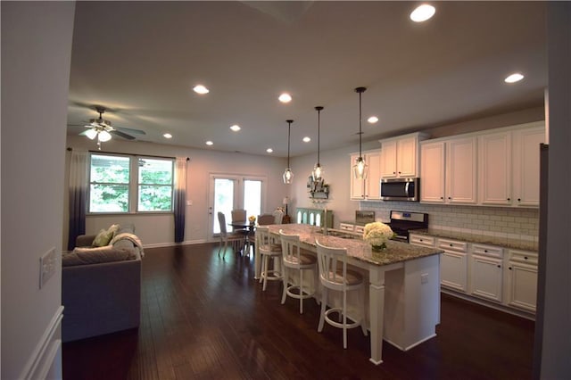 485 Broadmoor Dr, Braselton, GA 30517 - kitchen featuring appliances with stainless steel finishes, open floor plan, white cabinets, a breakfast bar area, and tasteful backsplash