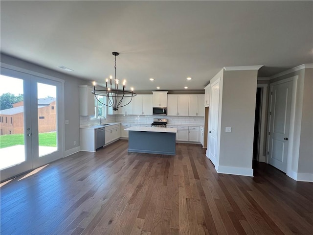 kitchen with white cabinets, sink, a kitchen island, stainless steel appliances, and dark hardwood / wood-style floors