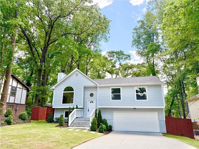 raised ranch with driveway, a garage, fence, and a front yard